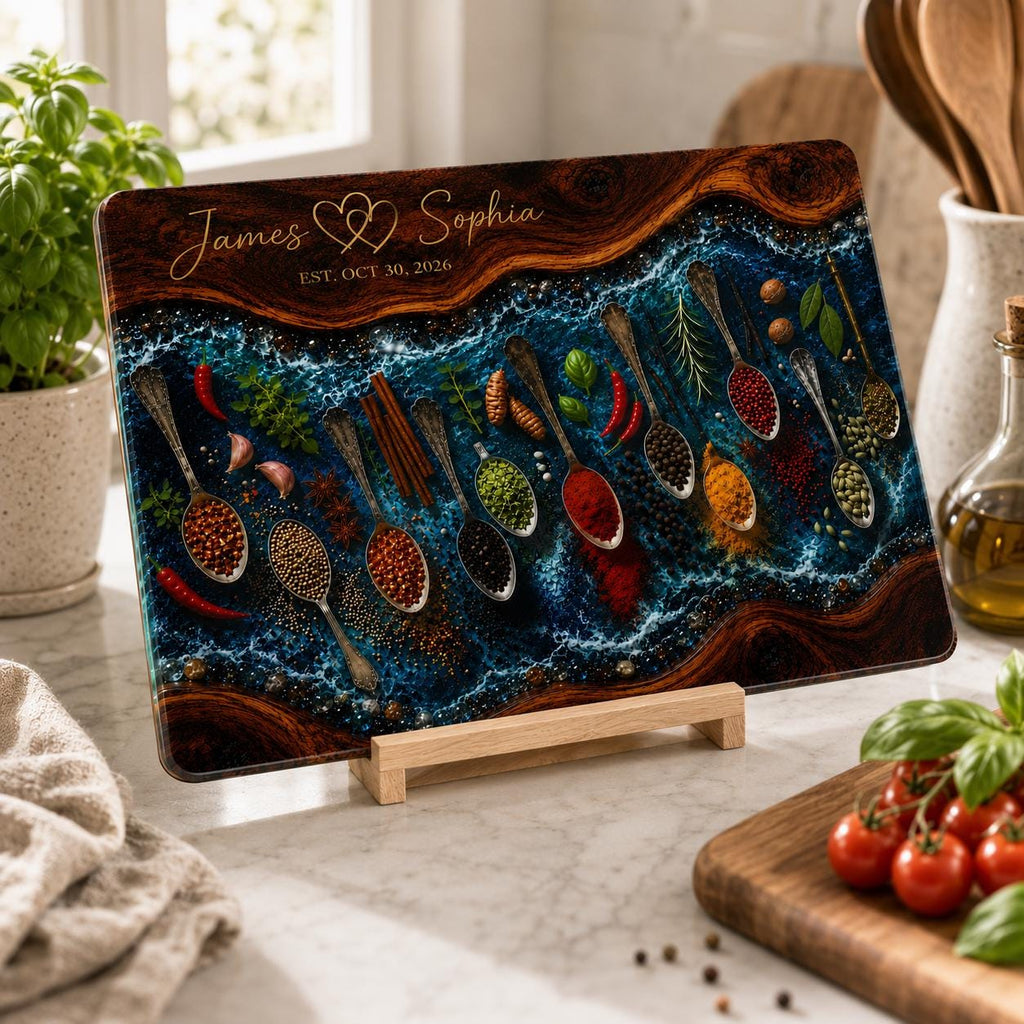 May include: A rectangular glass chopping board featuring a dark wood grain border and a central blue resin river design. The surface displays silver spoons filled with various spices and herbs, with the text James & Sophia EST. OCT 30, 2026.